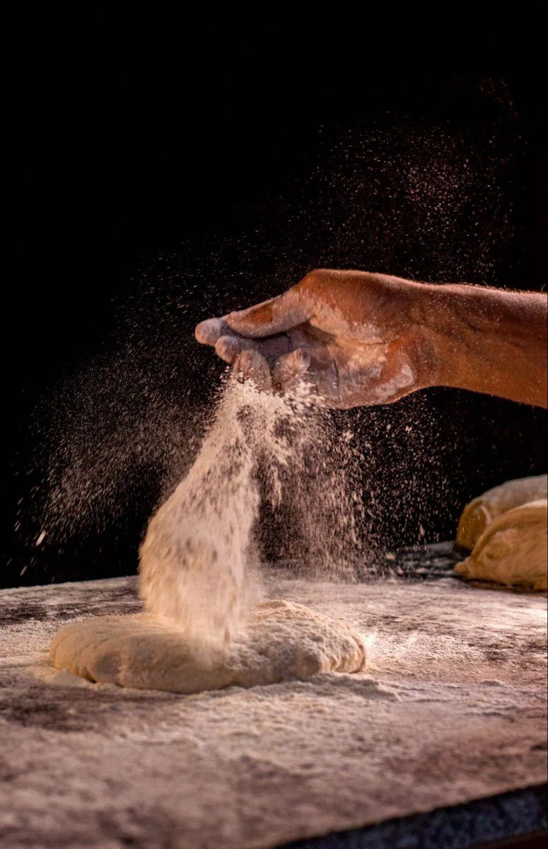 Le mani del pizzaiolo con farina e impasto
